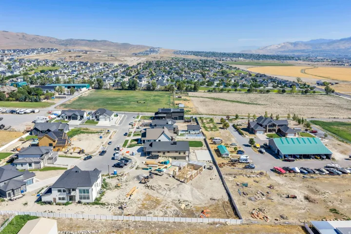 Expansive neighborhood featuring residential homes, developing construction sites, paved streets, and a mountainous backdrop