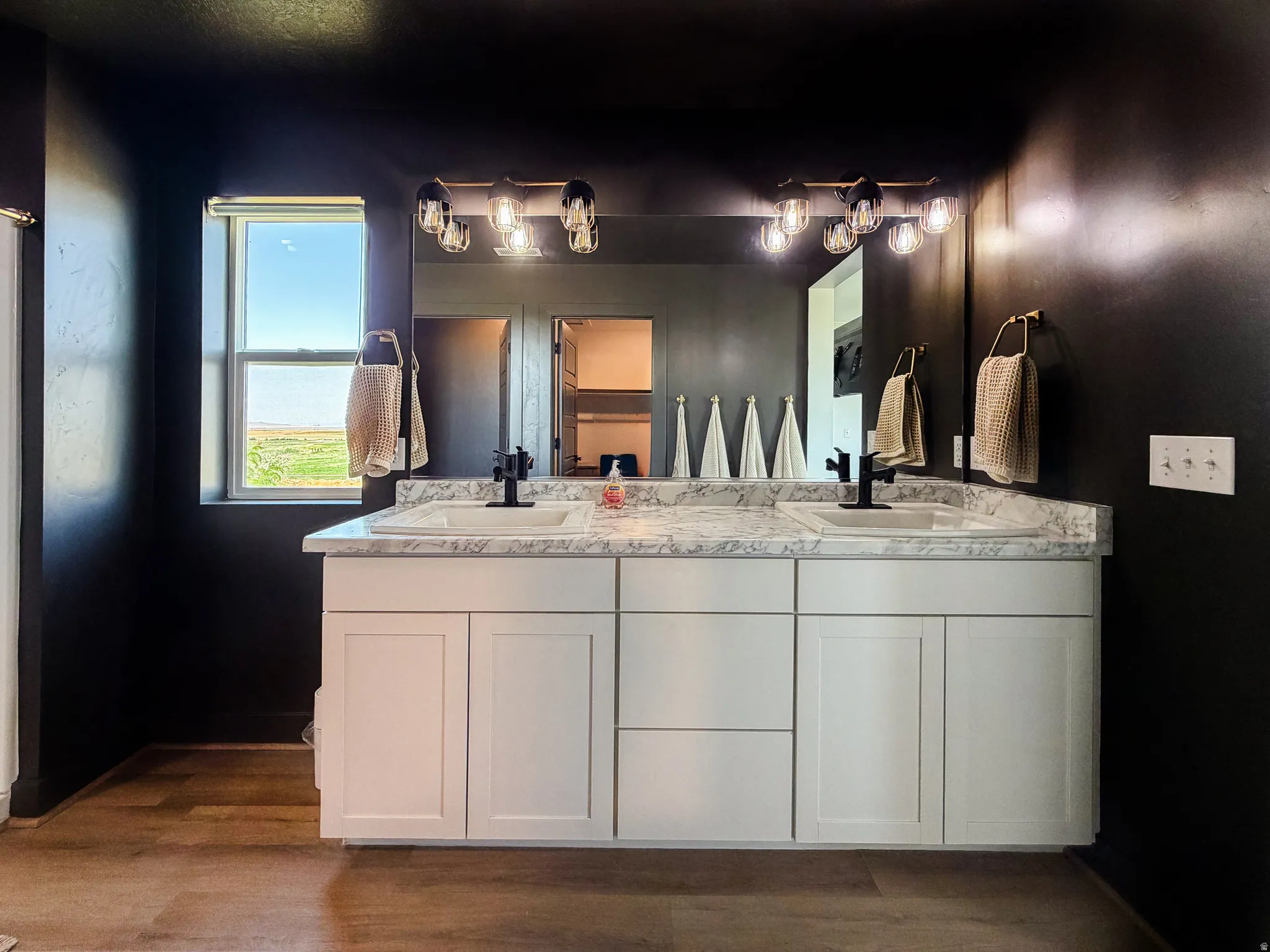 Double vanity with white shaker-style cabinetry, a white countertop, and dark-finish fixtures