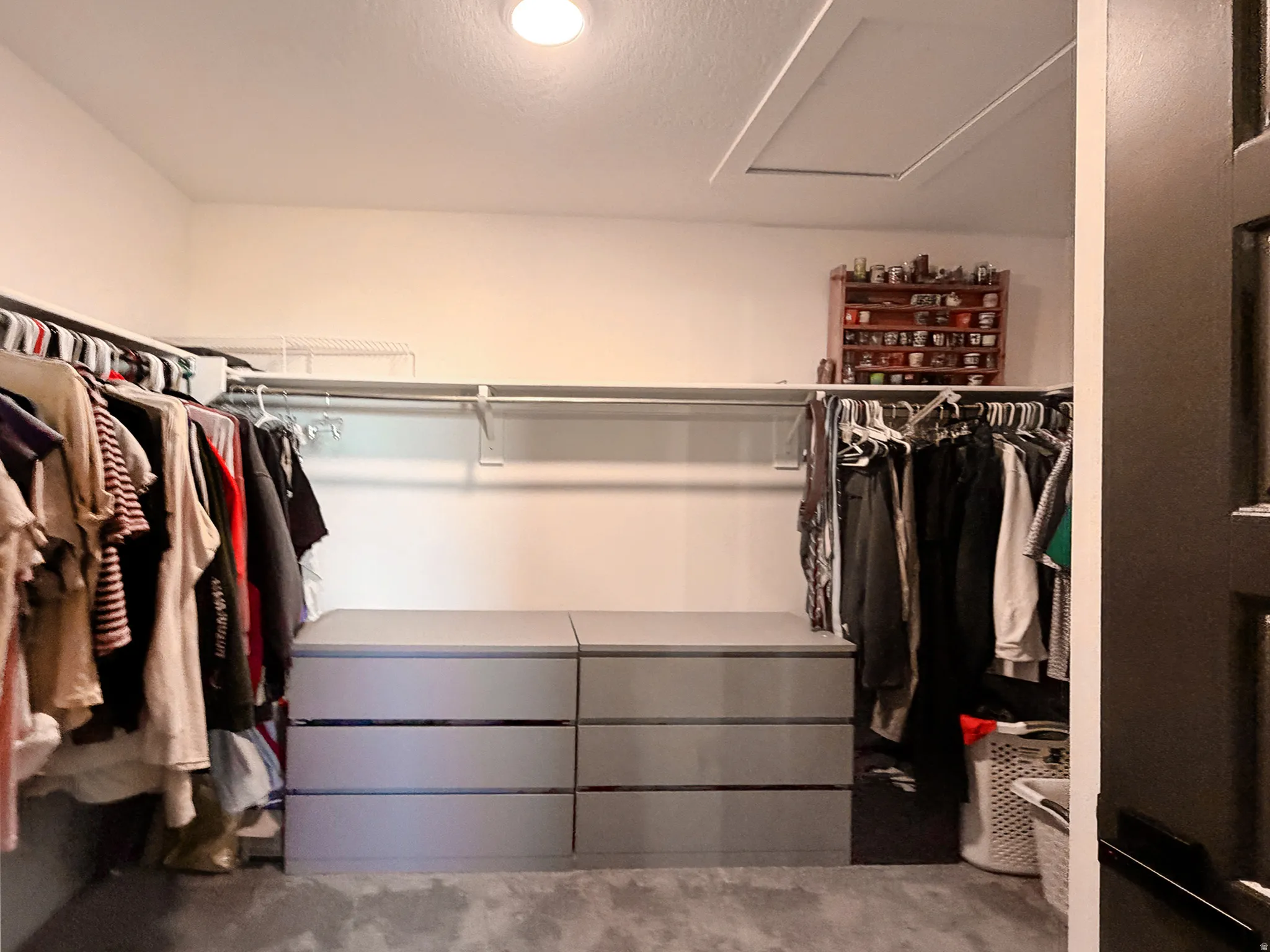 Walk-in closet featuring built-in storage, recessed lighting, and a pull-down attic access panel