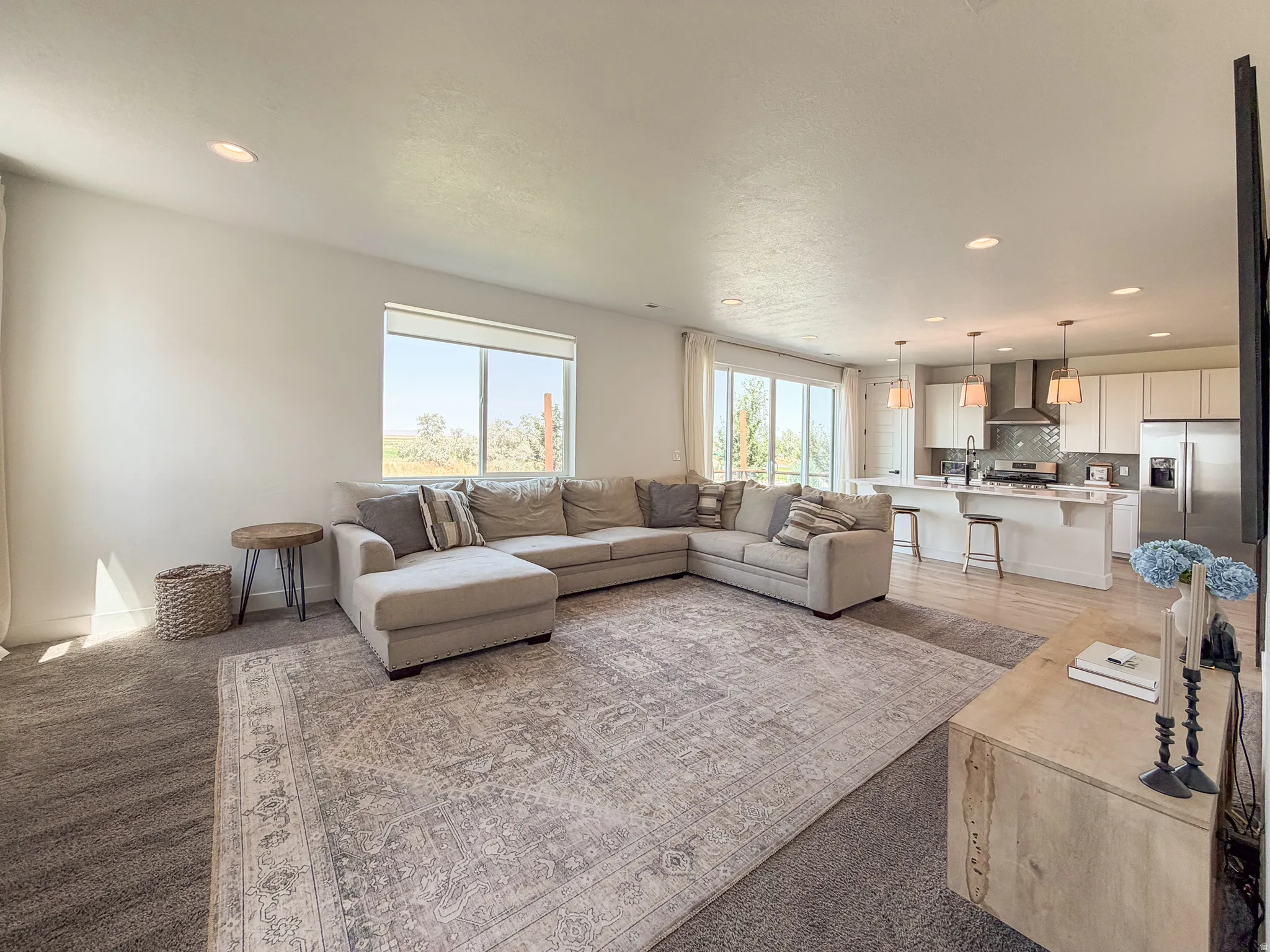 Spacious open-concept living area featuring recessed lighting, a large window, and sliding glass doors