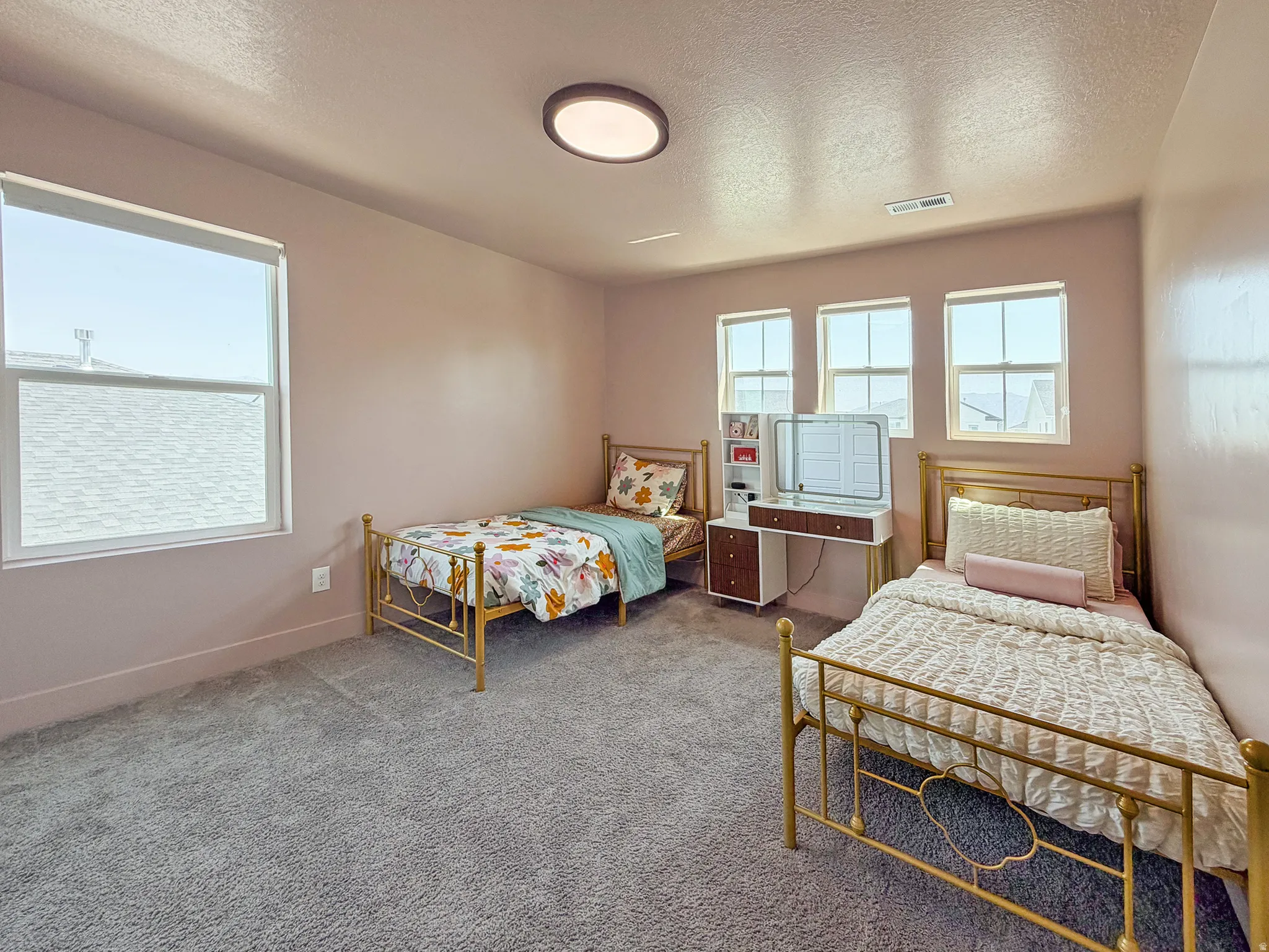 Spacious room featuring plush gray carpeting, a contemporary flush-mount ceiling light, and multiple windows providing ample natural illumination