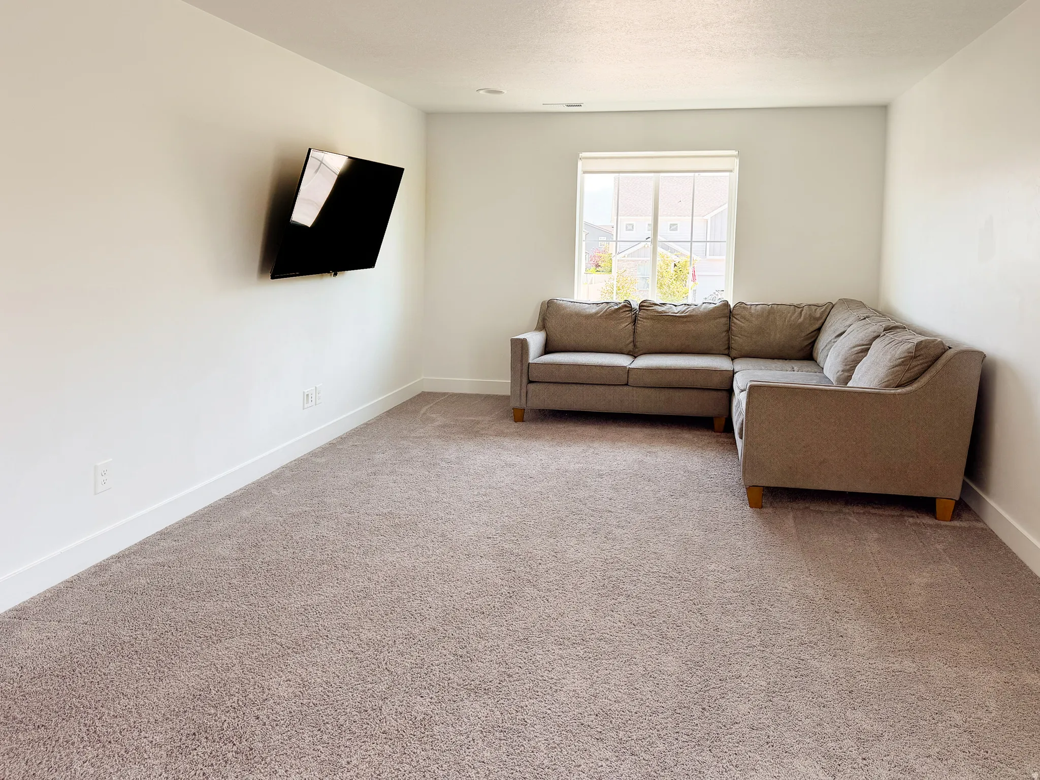 Carpeted room featuring a window with exterior views, white walls, and white baseboards