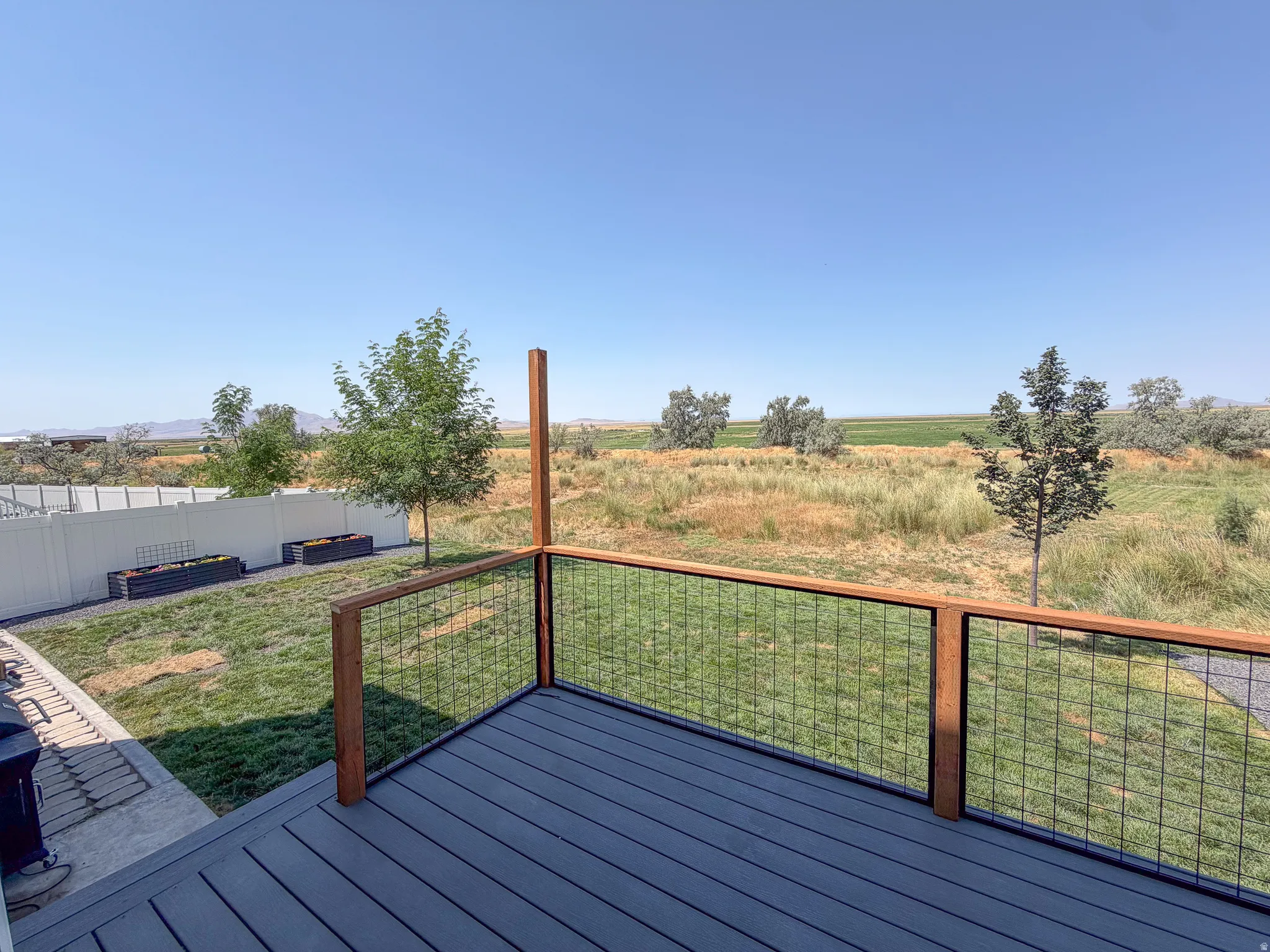 Expansive outdoor deck featuring composite decking, wood railings, and black wire infill