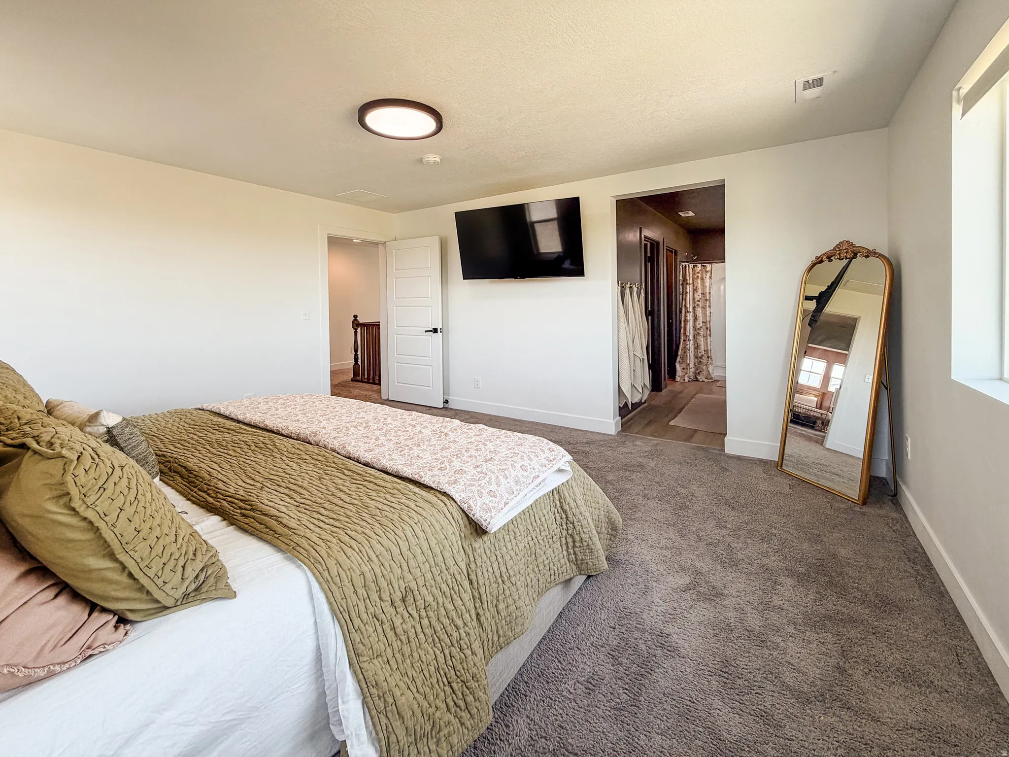 Carpeted bedroom featuring a flush-mount ceiling light fixture, white trim, and a window with white casing