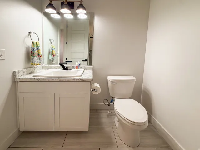 Bathroom featuring a floating vanity with a white countertop, an undermount sink, and a dark-finish faucet