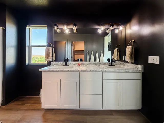Double vanity with white shaker-style cabinetry, a white countertop, and dark-finish fixtures