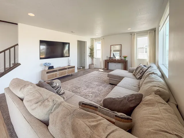 Spacious living area featuring light-colored walls and recessed lighting