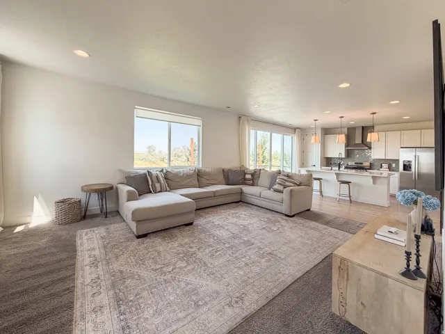 Spacious open-concept living area featuring recessed lighting, a large window, and sliding glass doors