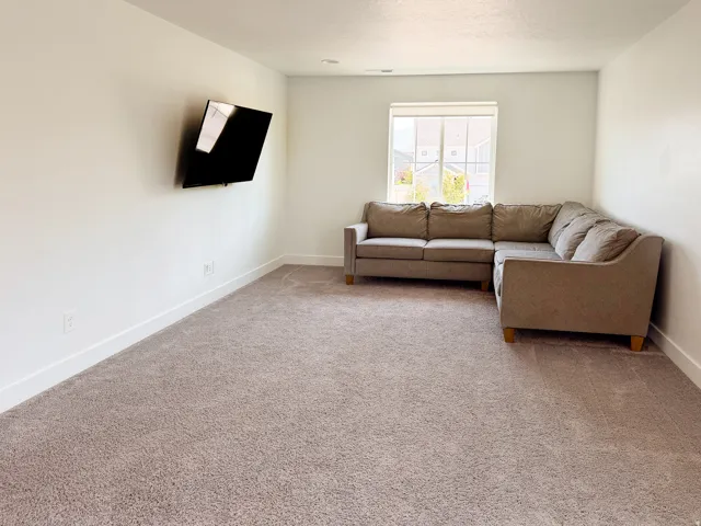 Carpeted room featuring a window with exterior views, white walls, and white baseboards