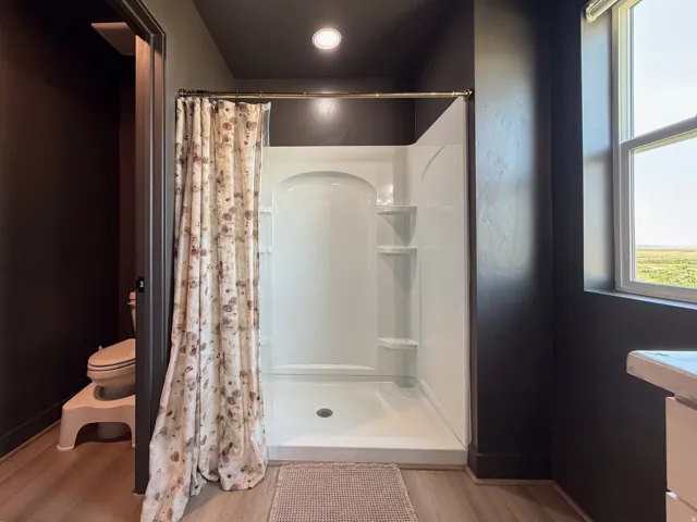Shower enclosure with integrated shelving, accompanied by a window offering exterior views