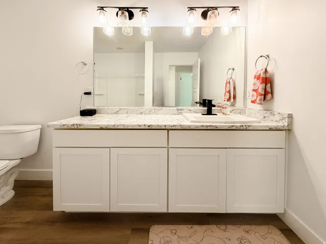 Dual vanity with white cabinetry, a light-toned countertop, and two framed mirrors