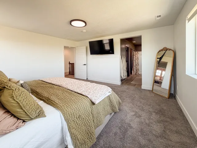 Carpeted bedroom featuring a flush-mount ceiling light fixture, white trim, and a window with white casing
