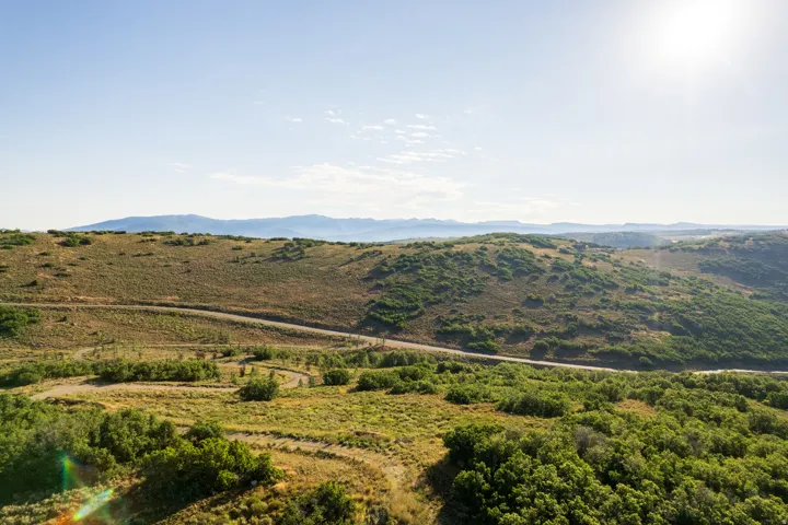 Expansive land parcel featuring undulating terrain, varied vegetation including shrubs and grasses, and distant mountain ranges