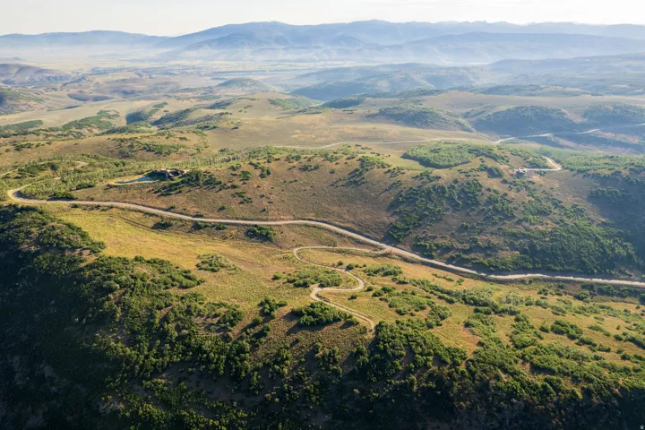 Expansive mountain landscape featuring varied topography, winding roads, and distant mountain ranges