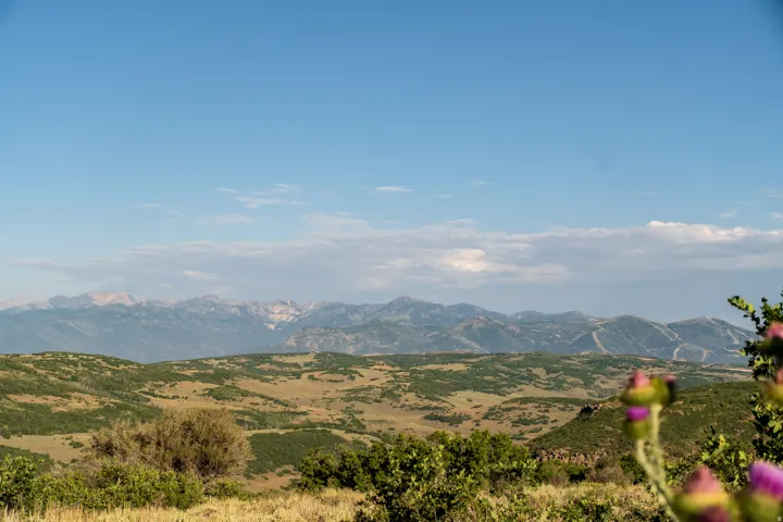 Expansive mountain range backdrop with distant peaks and rolling, verdant hills