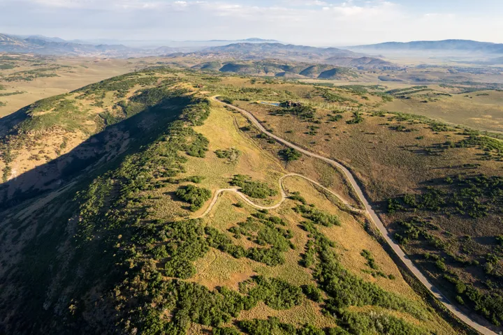 Expansive mountainous terrain featuring a winding paved road and a smaller unpaved path