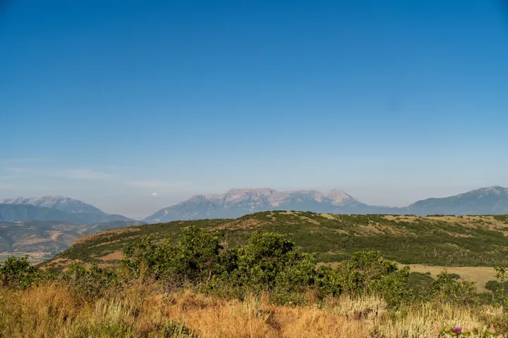 Expansive mountain range backdrop with rolling, tree-covered hills
