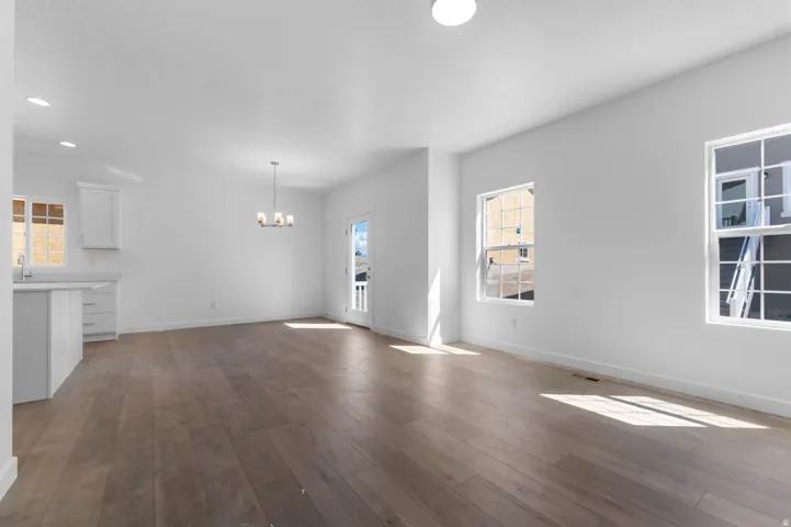 Open-concept living space featuring wood-finish flooring, white walls, and multiple windows