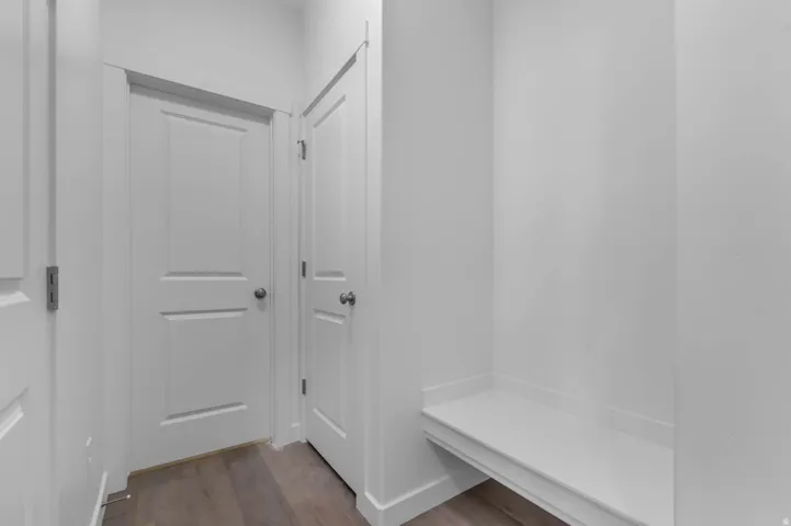 Entryway featuring a built-in bench, two panel doors, wood-finish flooring, and crisp white walls