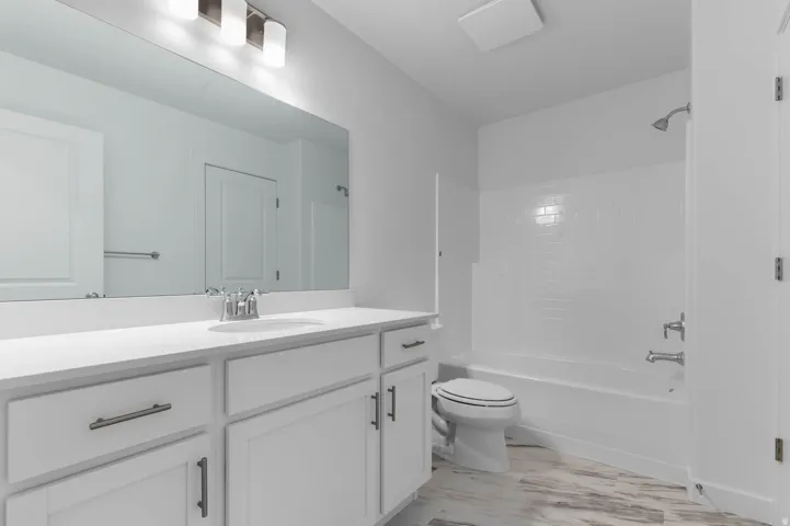Bathroom featuring a white vanity with integrated sink, brushed nickel faucet, and an expansive mirror