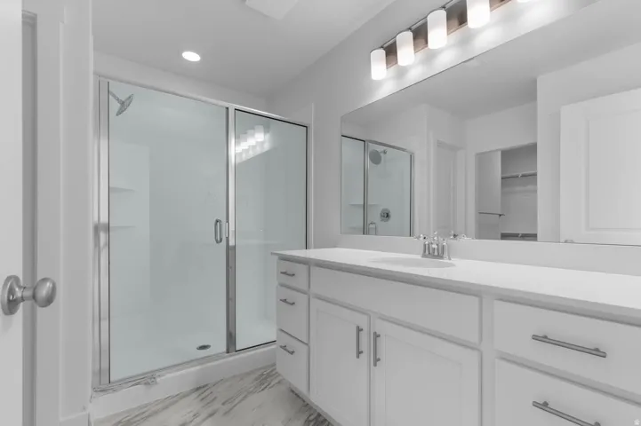 Contemporary bathroom featuring a glass-enclosed shower with built-in shelving, a double vanity with a light-colored countertop, and a large wall-mounted mirror