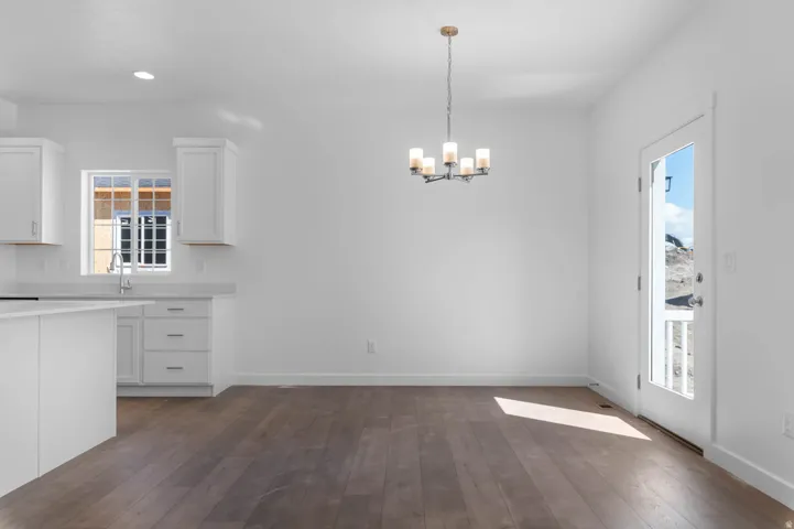Open-concept living space featuring wood-finish flooring, a modern chandelier, and a glass-paneled exterior door