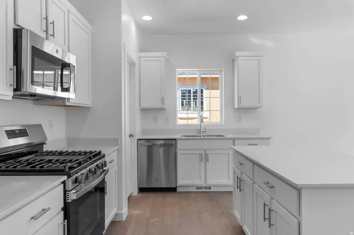Bright kitchen featuring white shaker cabinetry and light-toned countertops
