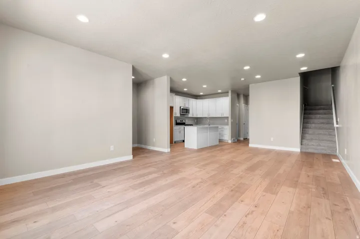 Open-concept living space featuring light wood-finish flooring, recessed lighting, and a neutral color palette