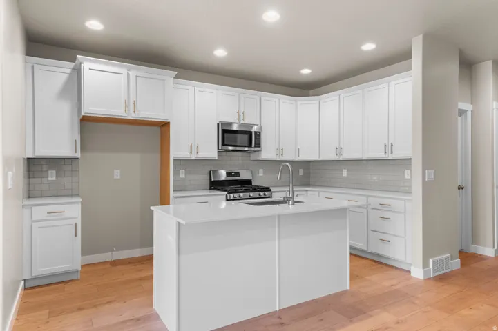 Modern kitchen featuring white cabinetry, a central island, and wood-finish flooring