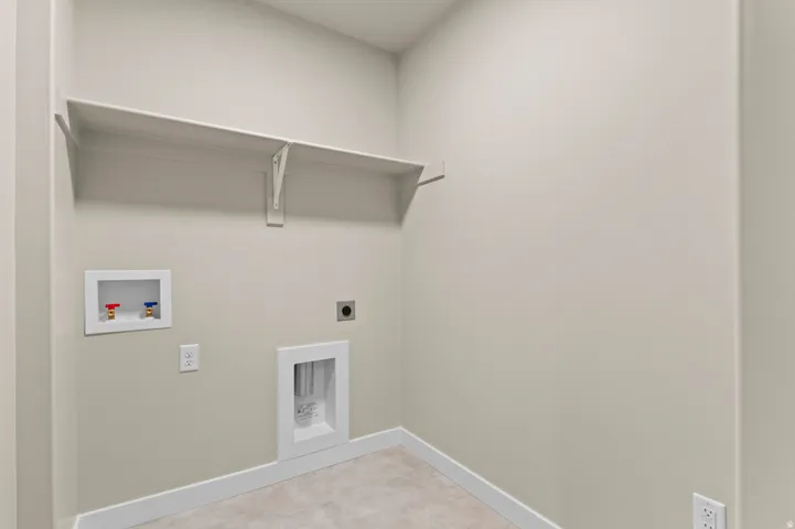 Dedicated laundry space featuring a built-in shelf, appliance hookups, and light-toned wall paint