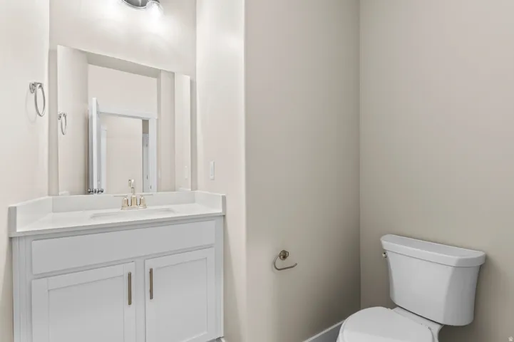 Bathroom featuring a white vanity with an undermount sink, a large mirror, and a modern toilet