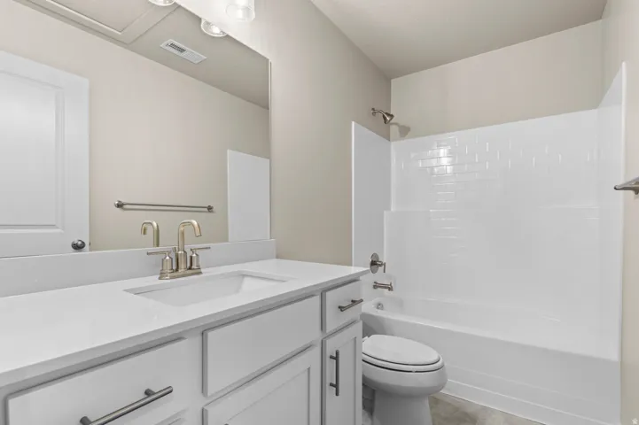 Bathroom featuring a single vanity with a white countertop and undermount sink, brushed nickel faucet, and white cabinetry with brushed nickel hardware