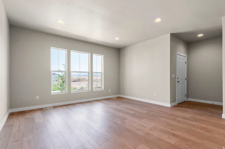 Spacious interior featuring wood-finish flooring, recessed lighting, and three large vertical windows