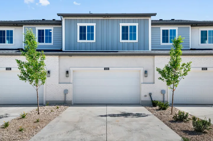 Contemporary townhome exterior featuring light stucco and brick accents
