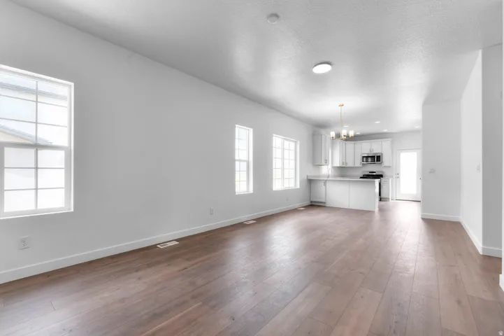 Open-concept living area featuring wood-finish flooring, white walls, multiple windows, and recessed lighting