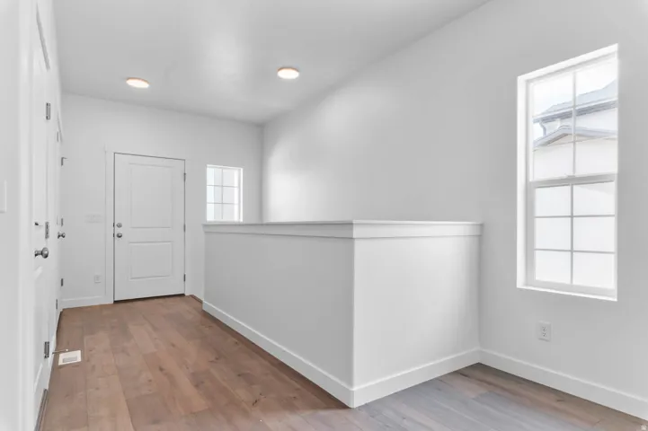 Bright interior space featuring wood-finish flooring, white walls, and recessed lighting