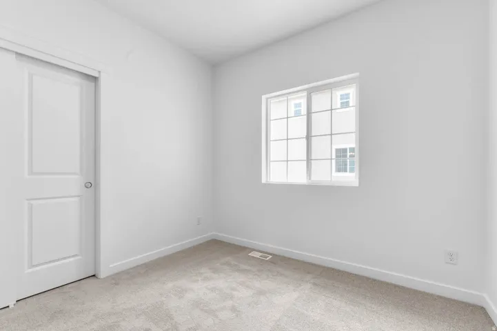 Carpeted room featuring a double-paned window with grids, white trim, and a white interior door