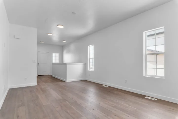 Open concept living area featuring wood-finish flooring, recessed lighting, and multiple windows