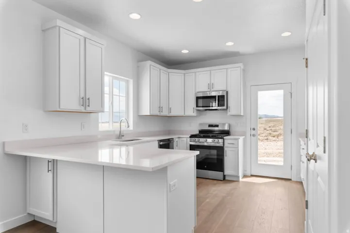 Kitchen featuring white shaker cabinetry, light-toned countertops, stainless steel appliances, and recessed lighting