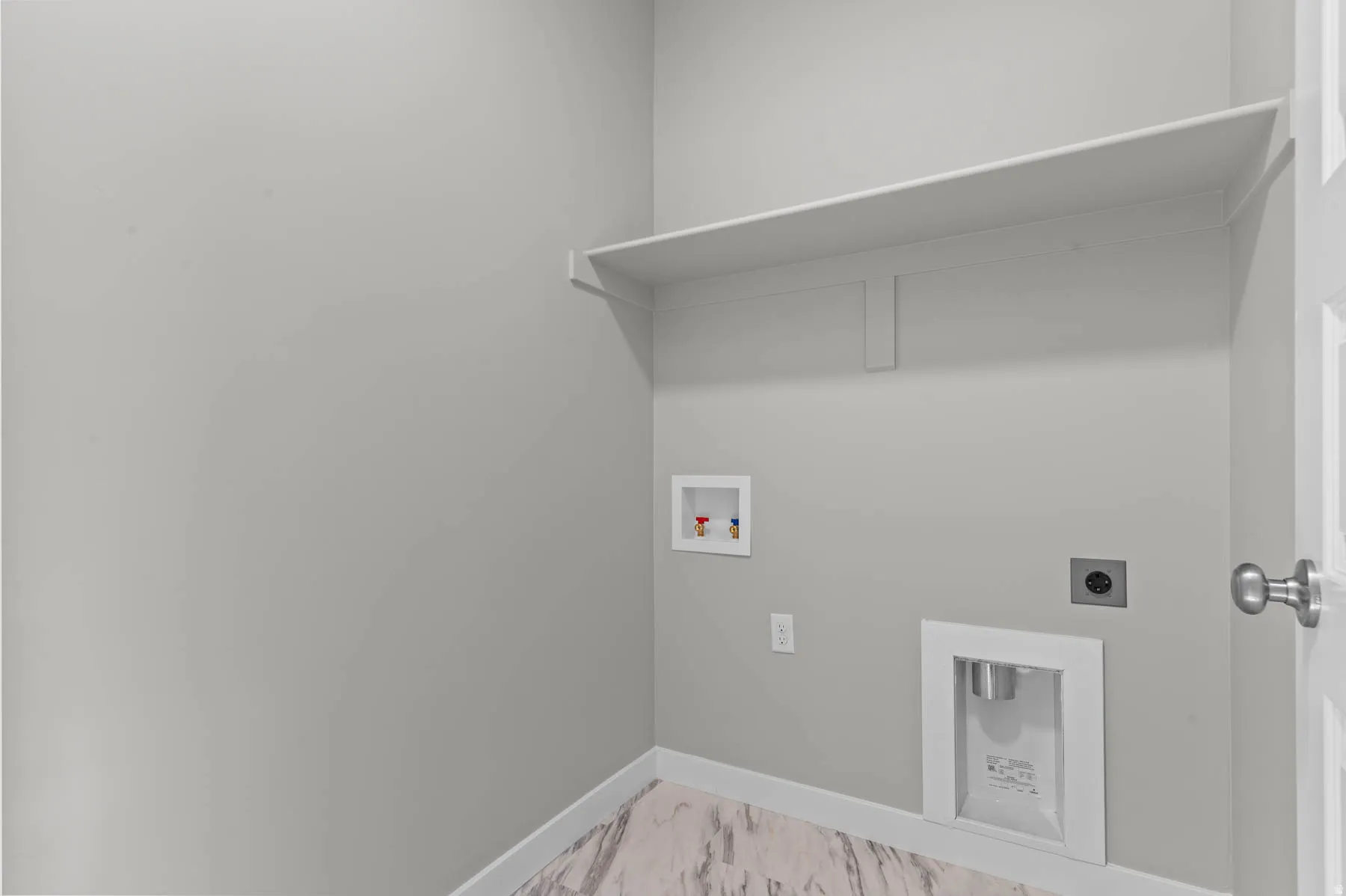 Dedicated laundry area featuring a wall-mounted shelf, light gray wall paint, and wood-finish flooring