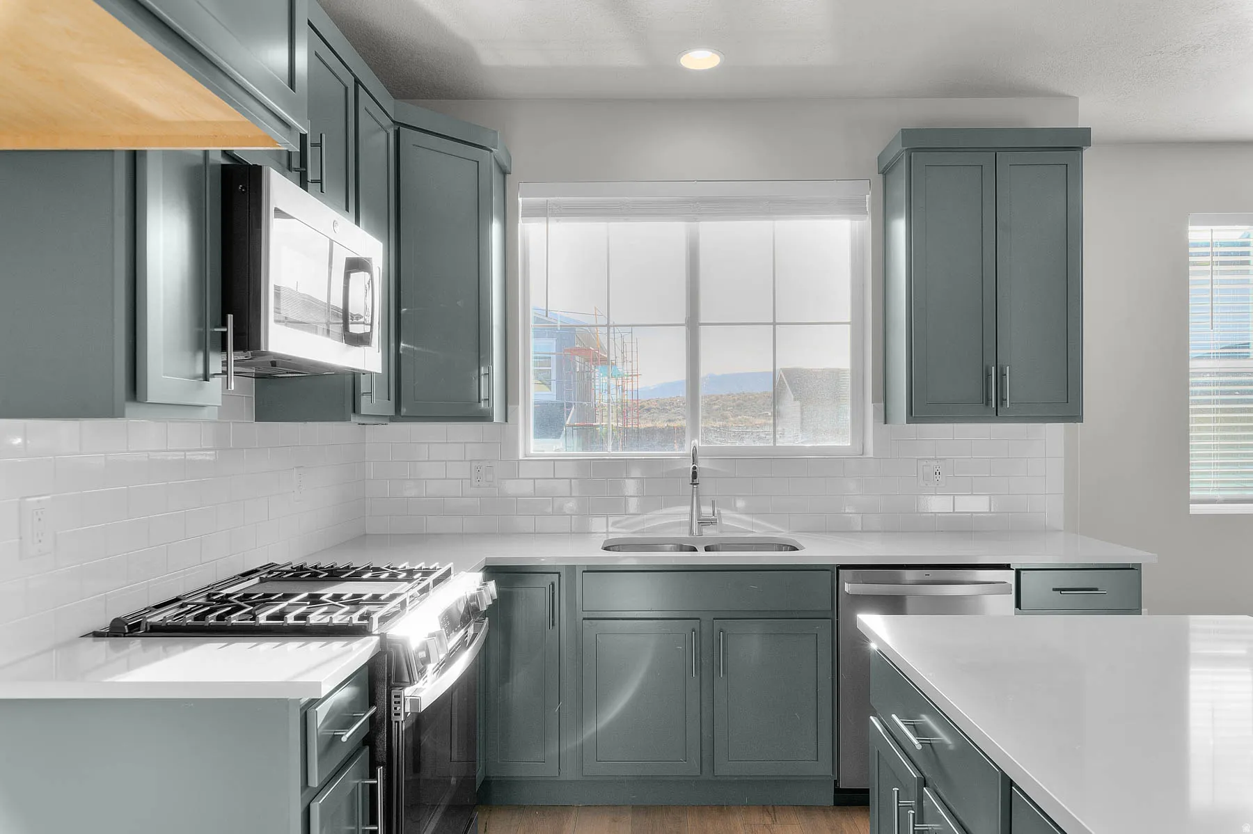 Kitchen featuring shaker-style cabinetry, stainless steel appliances, white subway tile backsplash, and light-tone countertops