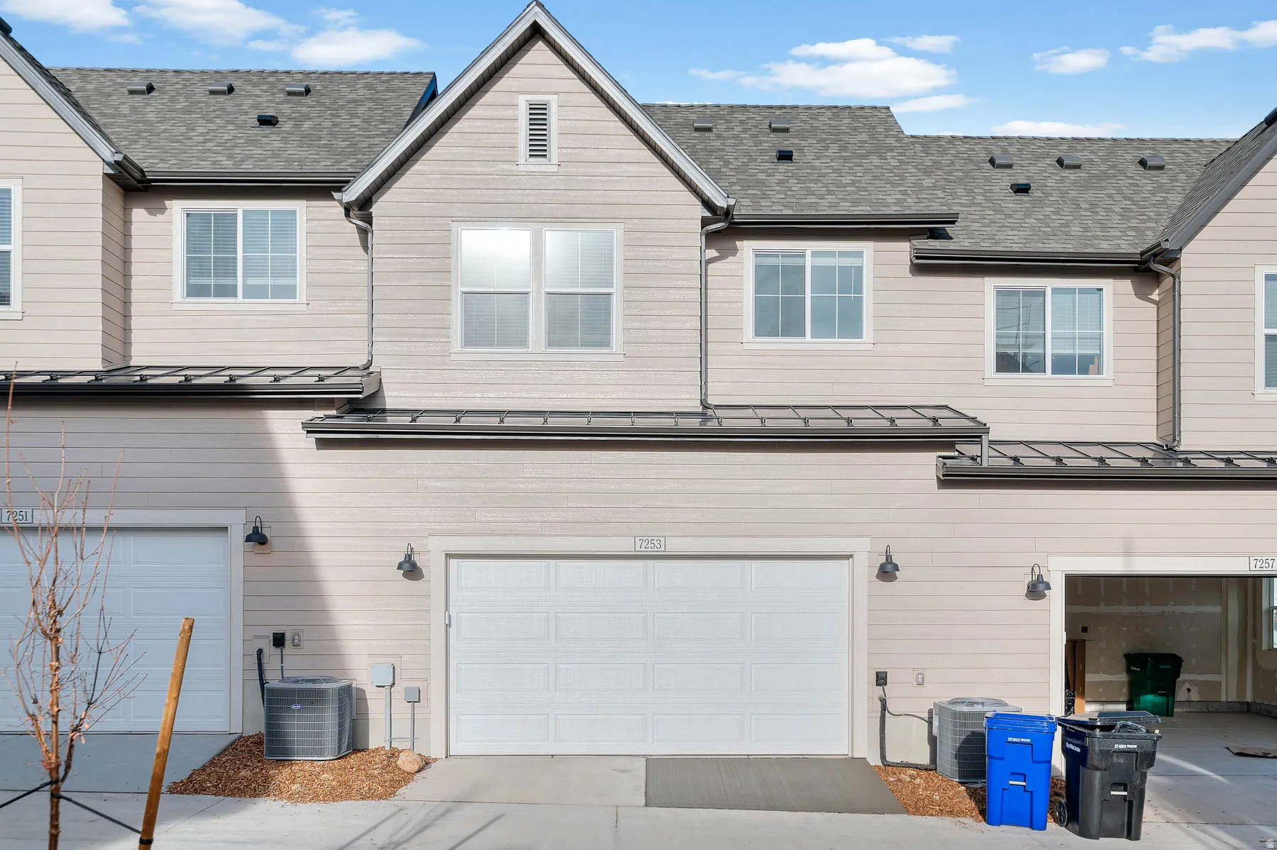 Exterior featuring horizontal siding, multiple windows, an attached garage, a gray shingle roof, and exterior lighting fixtures