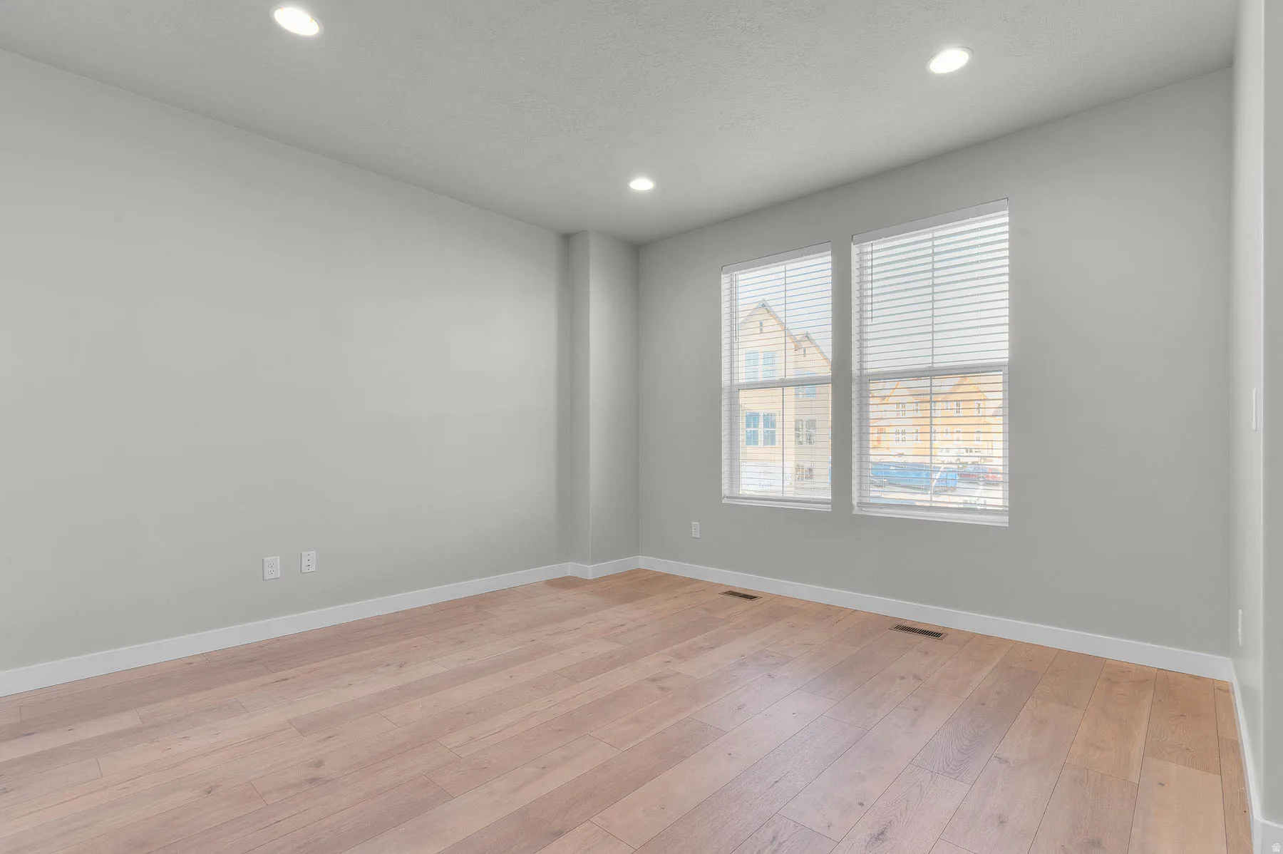 Light-toned wood-finish flooring complements the neutral wall color
