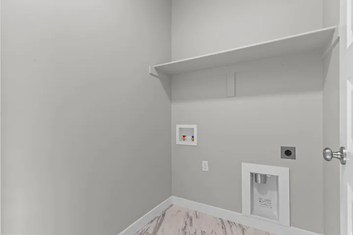 Dedicated laundry area featuring a wall-mounted shelf, light gray wall paint, and wood-finish flooring