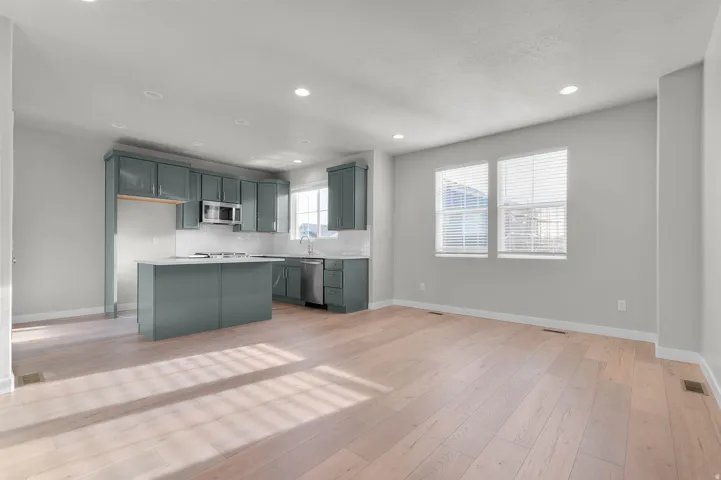 Open-concept living space featuring light wood-finish flooring, recessed lighting, and crisp white walls