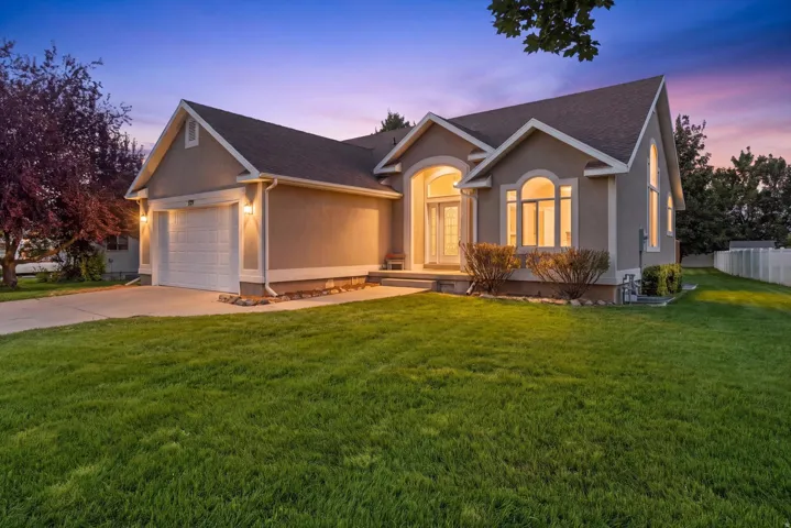 Stucco exterior with a pitched roof, arched windows, covered entry, and attached garage