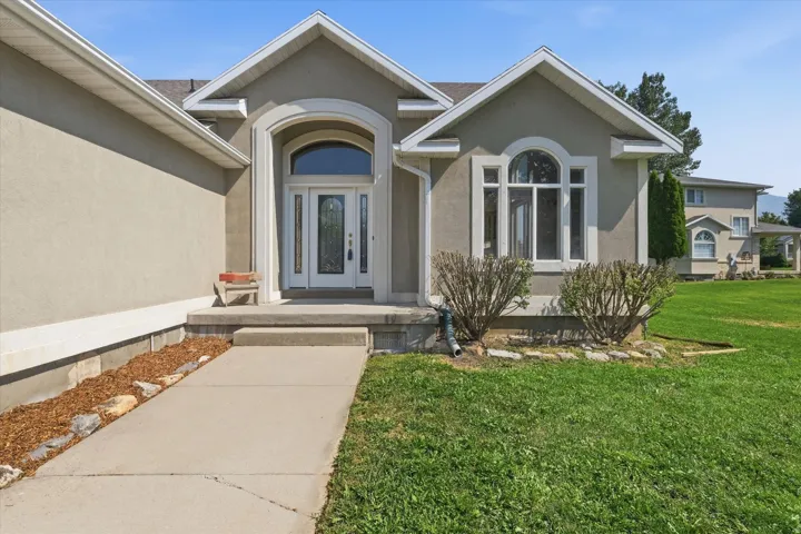 Stucco exterior with an arched entry, a decorative glass front door, and an arched window