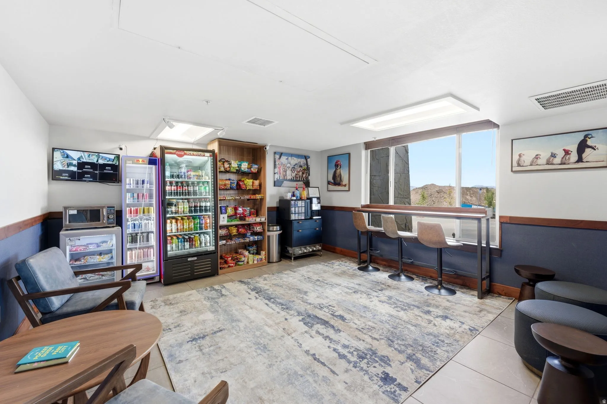 Open common area featuring a wide window with a built-in bar table, modern pendant lighting, and a patterned area rug