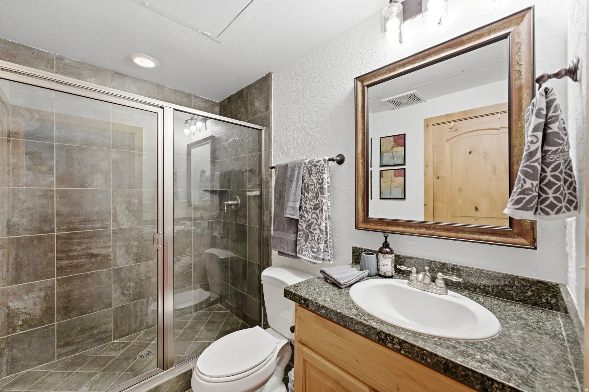 Bathroom featuring a glass-enclosed shower with tile surround, a built-in shower bench, and recessed lighting