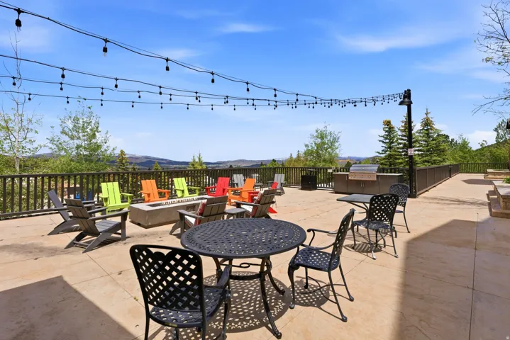 Expansive outdoor patio featuring a built-in fire pit, string lighting, and an outdoor grilling station